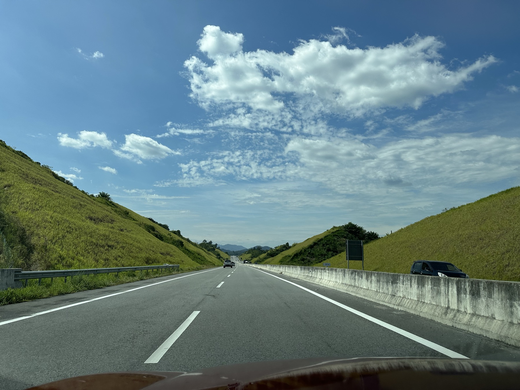 Highway through green hills under open sky in Malaysia